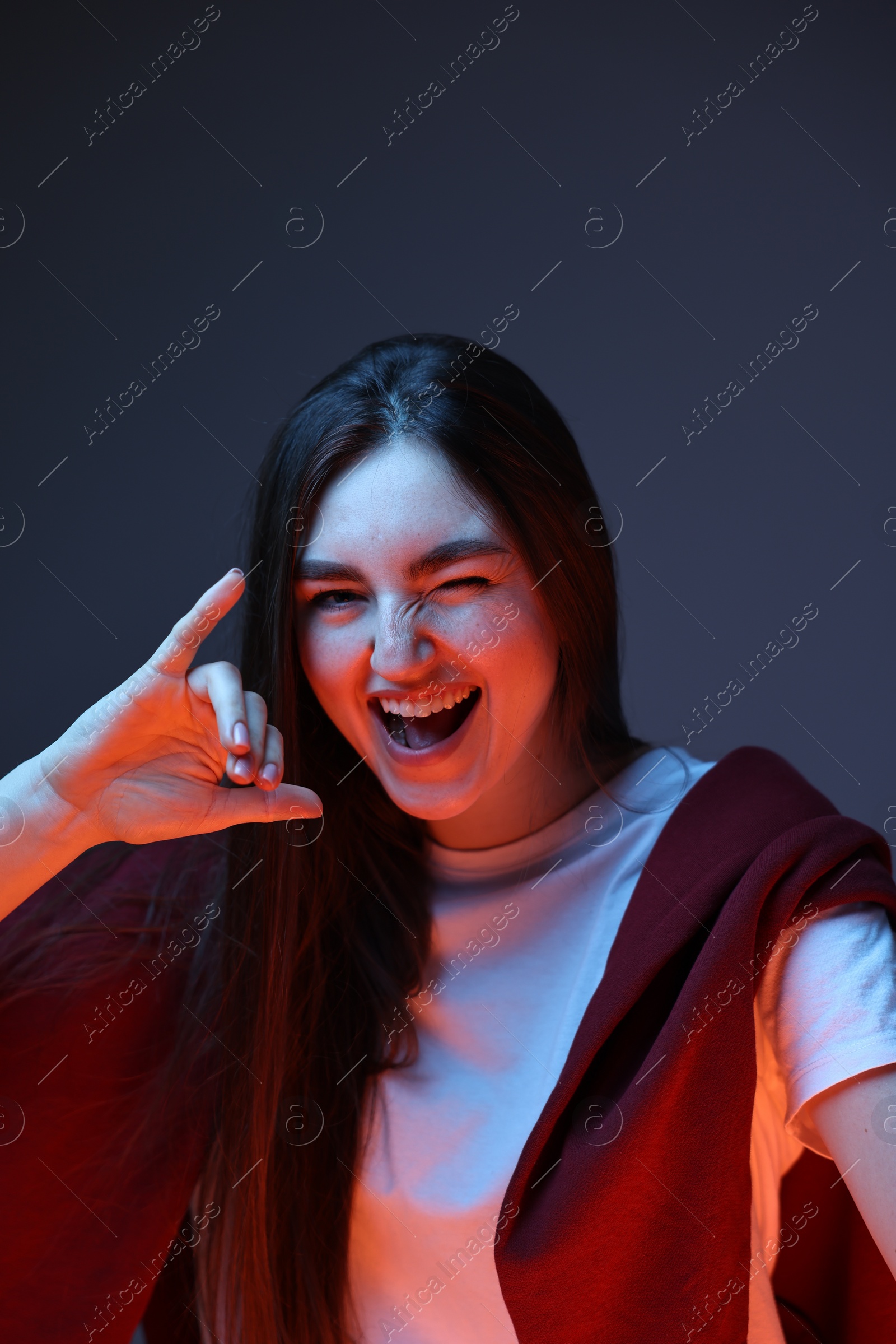 Photo of Portrait of happy woman gesturing on dark blue background in neon lights