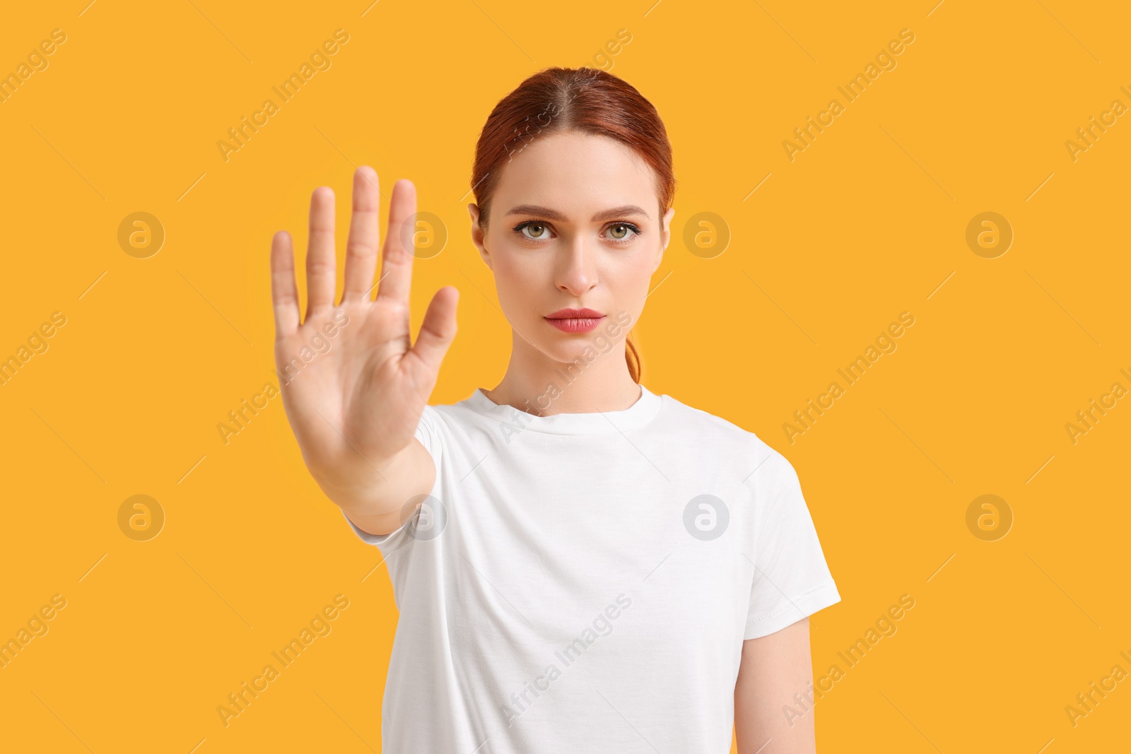 Photo of Woman showing stop gesture on yellow background
