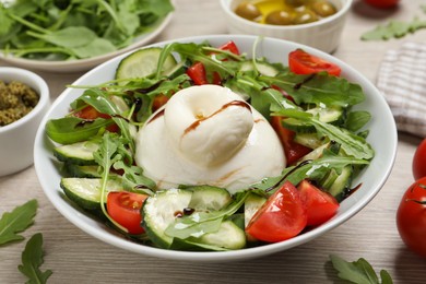 Photo of Delicious burrata salad served on wooden table, closeup