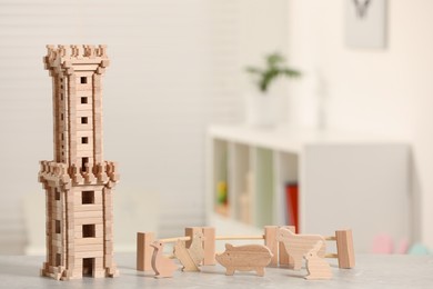 Wooden tower, animals and fence on table indoors, space for text. Children's toys