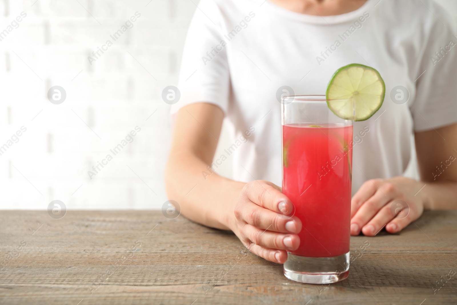 Photo of Young woman with glass of tasty refreshing drink at wooden table, closeup