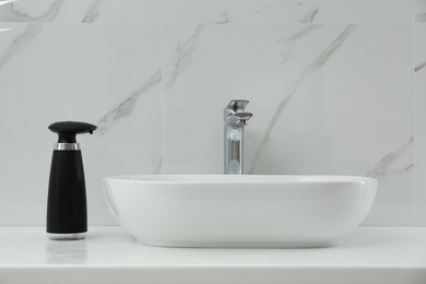 Photo of Modern automatic soap dispenser near sink in bathroom