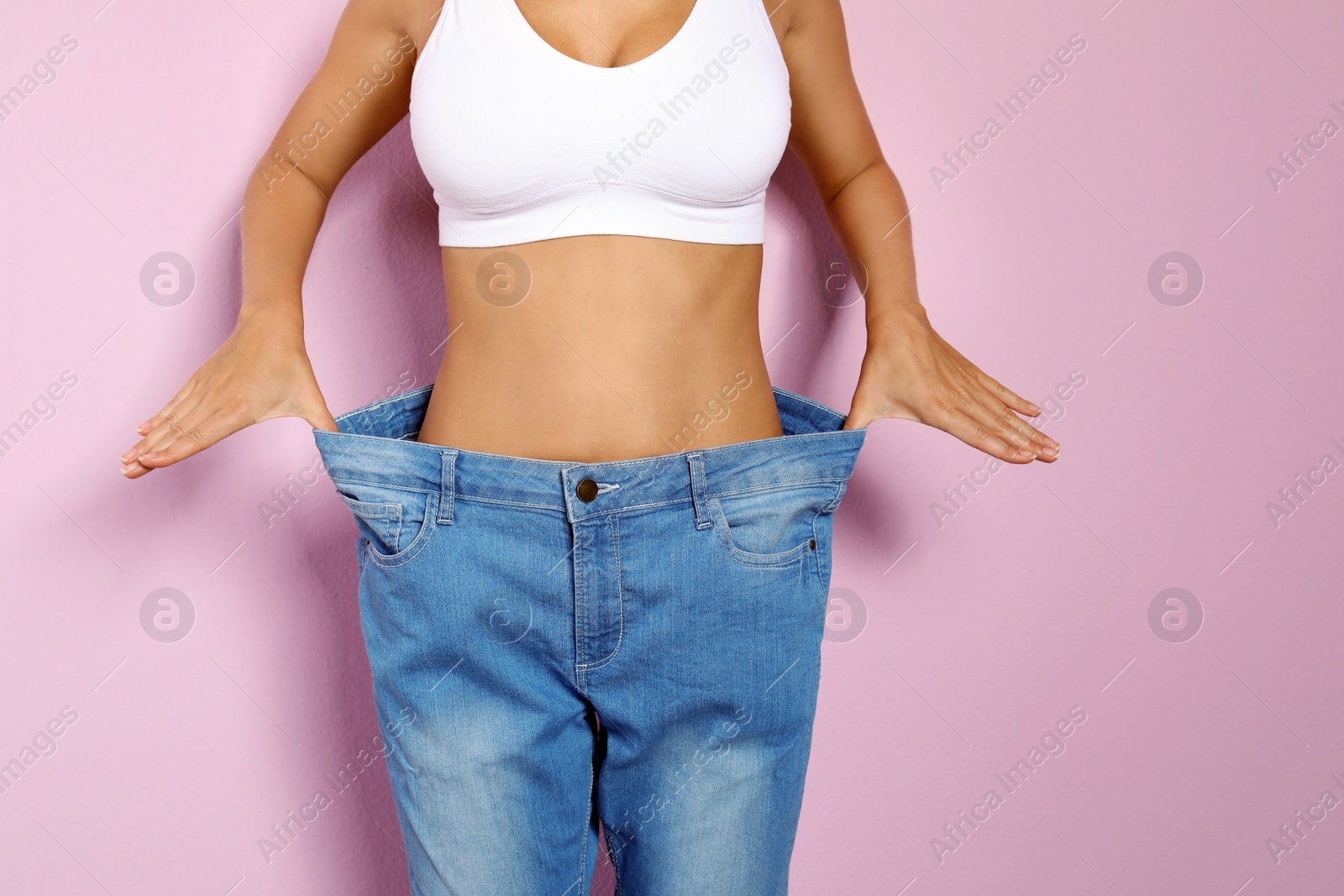 Photo of Slim woman in oversized jeans on color background. Healthy diet