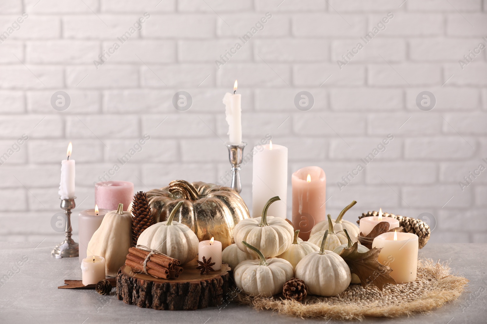 Photo of Beautiful composition with pumpkins and burning candles on table