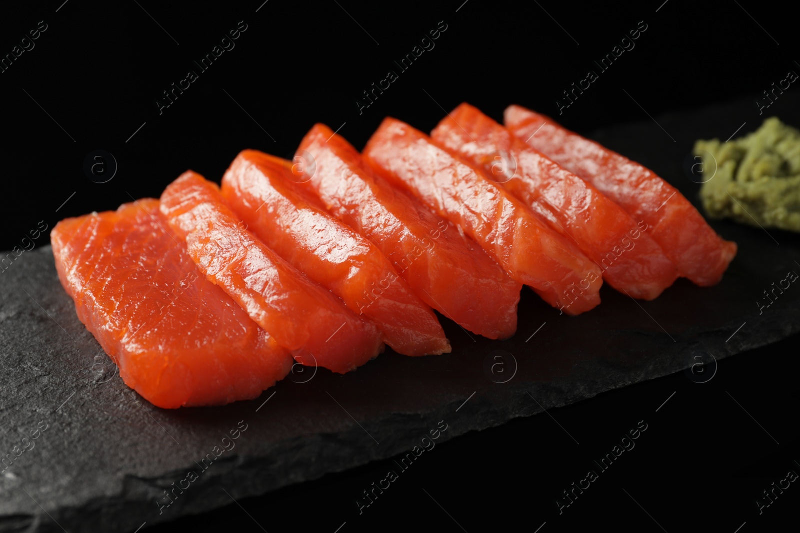 Photo of Delicious salmon sashimi and wasabi on black background, closeup