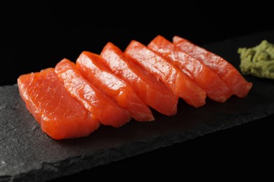 Photo of Delicious salmon sashimi and wasabi on black background, closeup