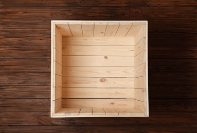 Photo of Open empty wooden crate on color background, top view