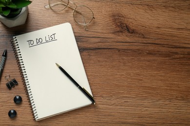 Flat lay composition with unfilled To Do list in notebook and glasses on wooden table, space for text