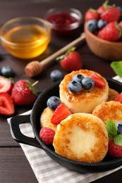 Photo of Delicious cottage cheese pancakes with fresh berries and honey on wooden table, closeup
