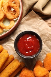 Tasty chicken nuggets, fried onion rings, cheese sticks and ketchup on table, flat lay