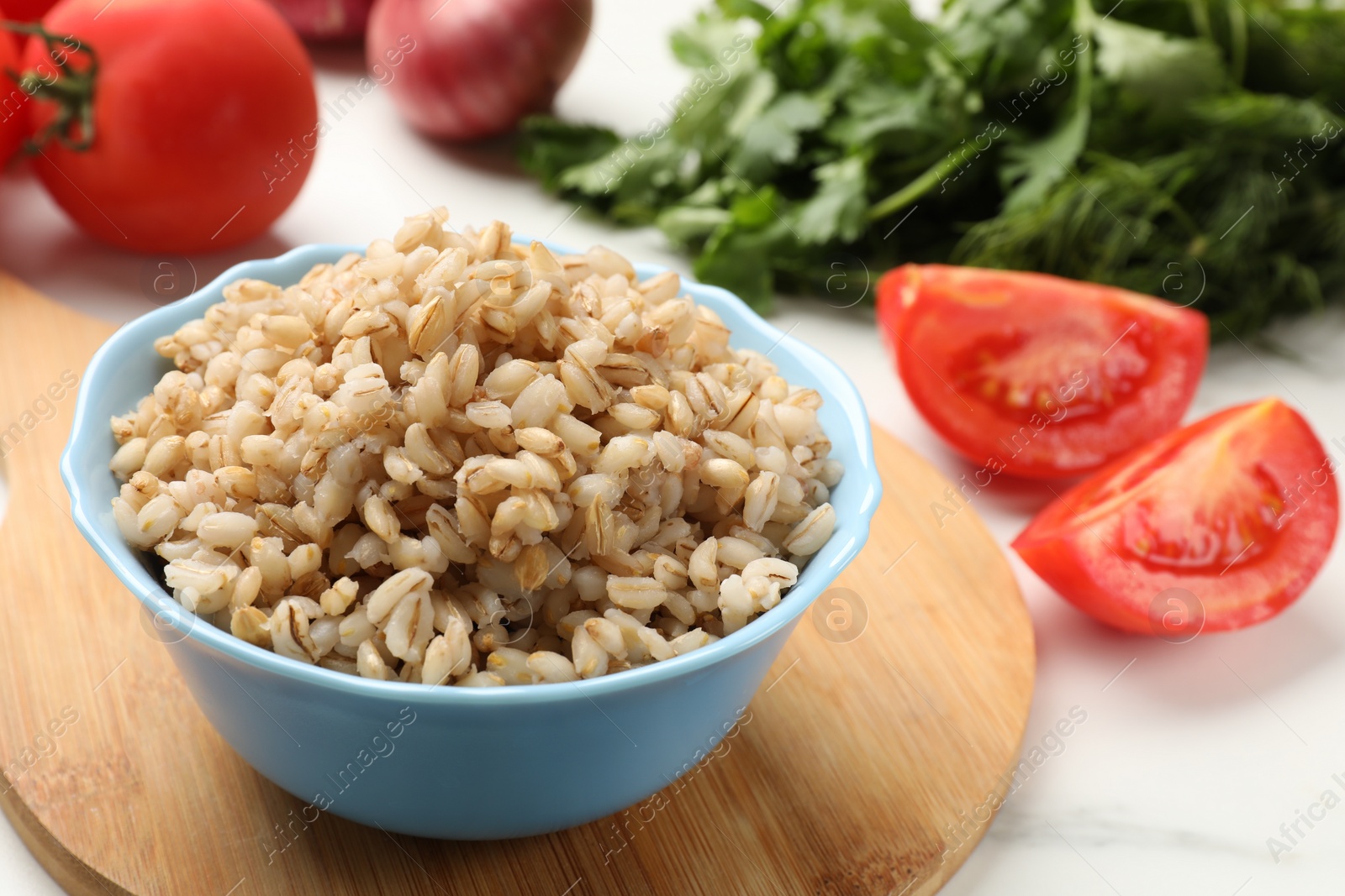 Photo of Delicious pearl barley in bowl on white table, closeup