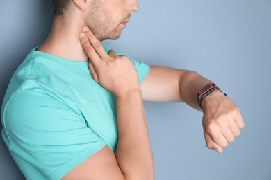 Photo of Young man checking pulse on color background, closeup