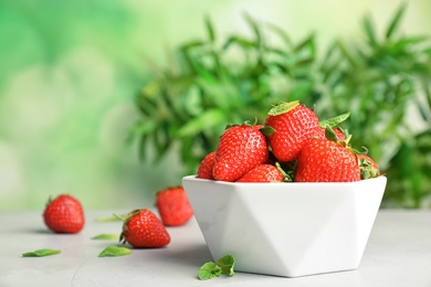 Bowl with ripe red strawberries on table