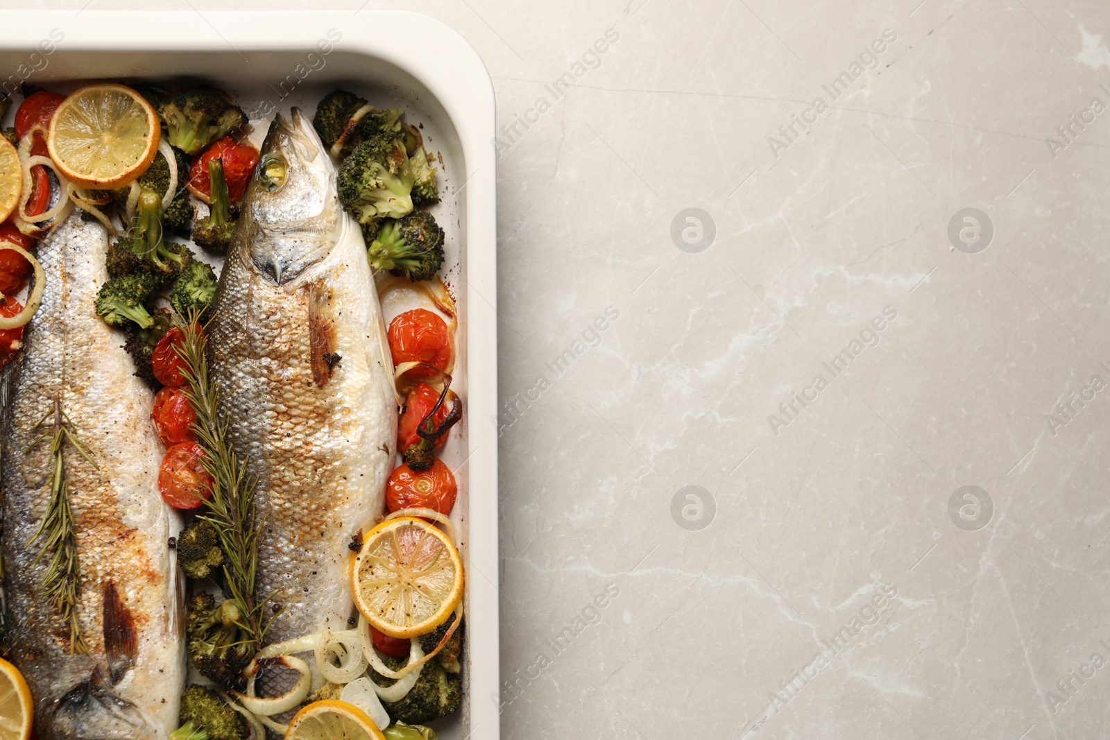 Photo of Delicious fish with vegetables and lemon in baking dish on light marble table, top view. Space for text