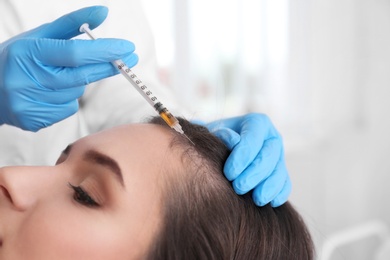 Young woman with hair loss problem receiving injection in salon, closeup