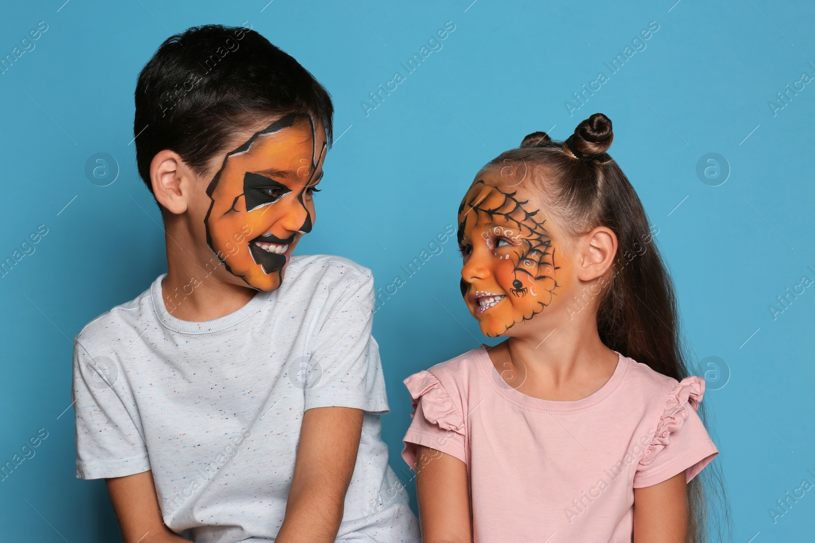 Photo of Cute little children with face painting on blue background