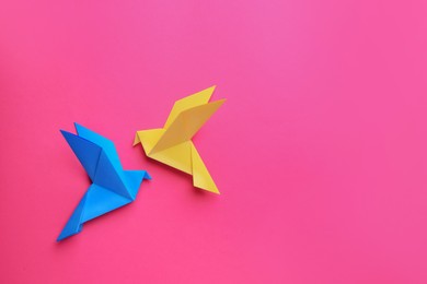 Photo of Beautiful colorful origami birds on pink background, flat lay. Space for text