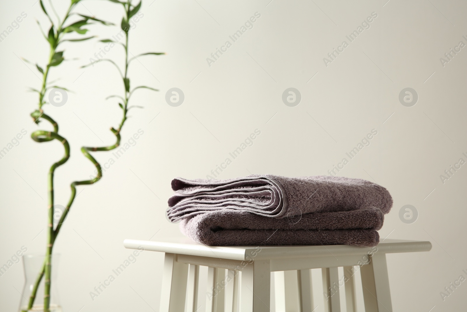 Photo of Violet towels on stool against white wall. Space for text