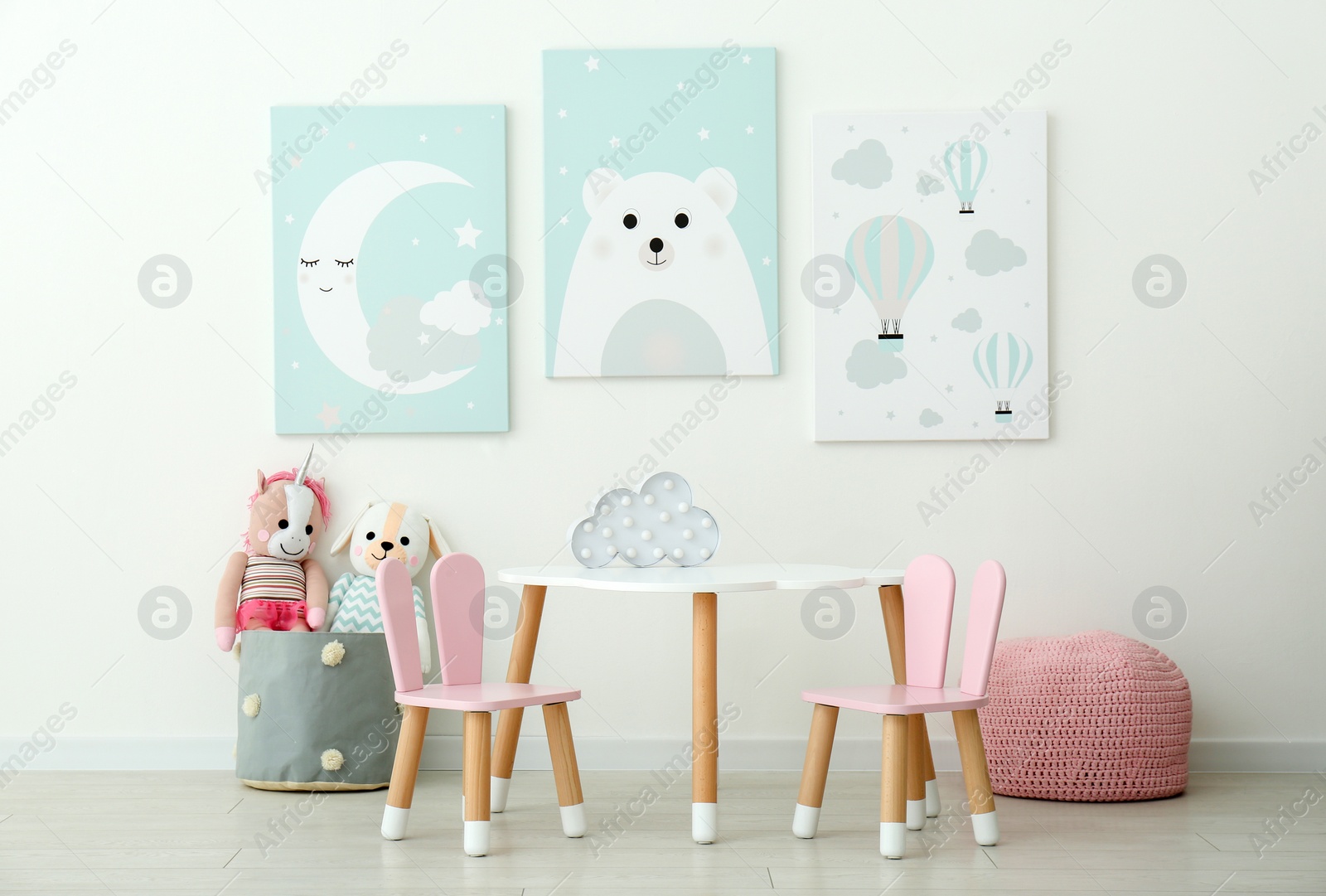 Photo of Adorable wall art, table and chairs with bunny ears in children's room interior