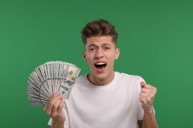 Handsome man with dollar banknotes on green background