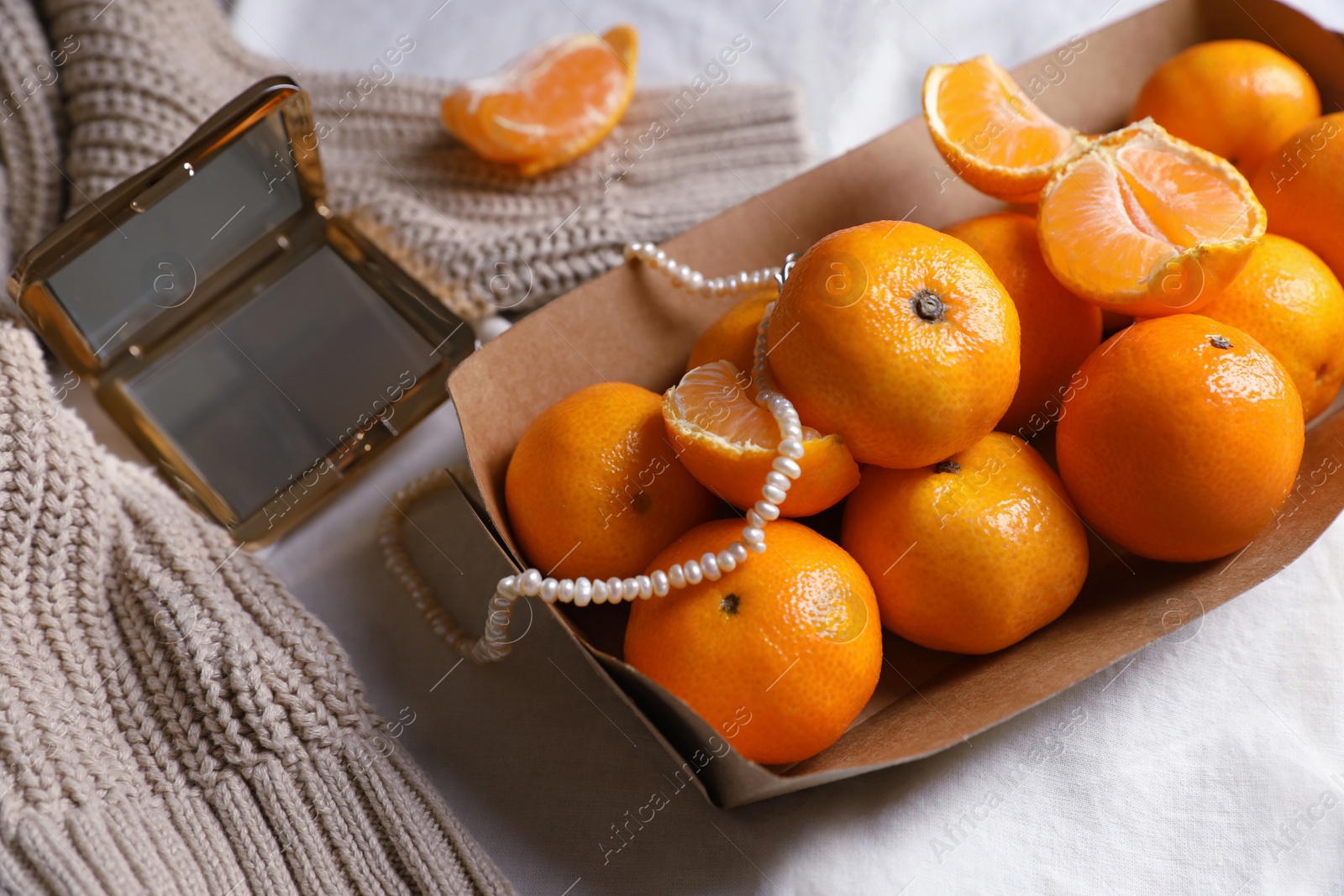 Photo of Paper box with fresh ripe tangerines and decor on white cloth, above view