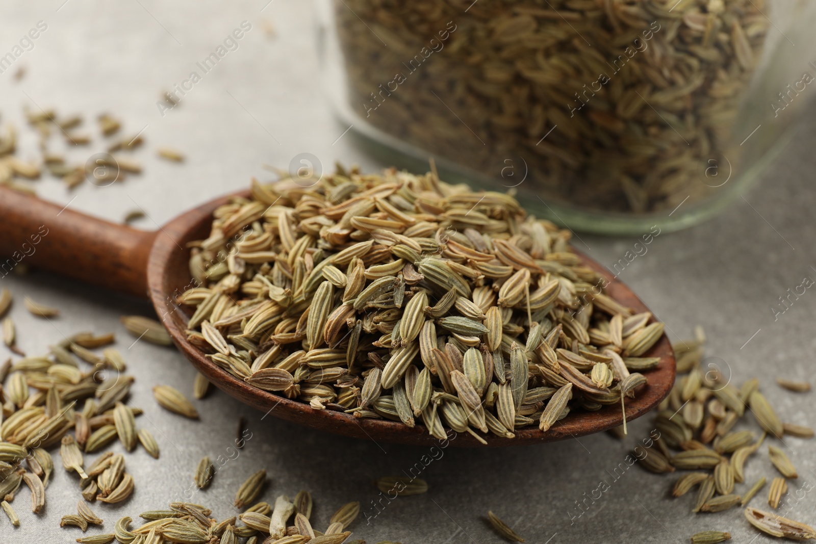 Photo of Wooden spoon with fennel seeds on grey table, closeup