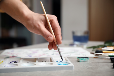 Woman painting with watercolor at grey stone table, closeup