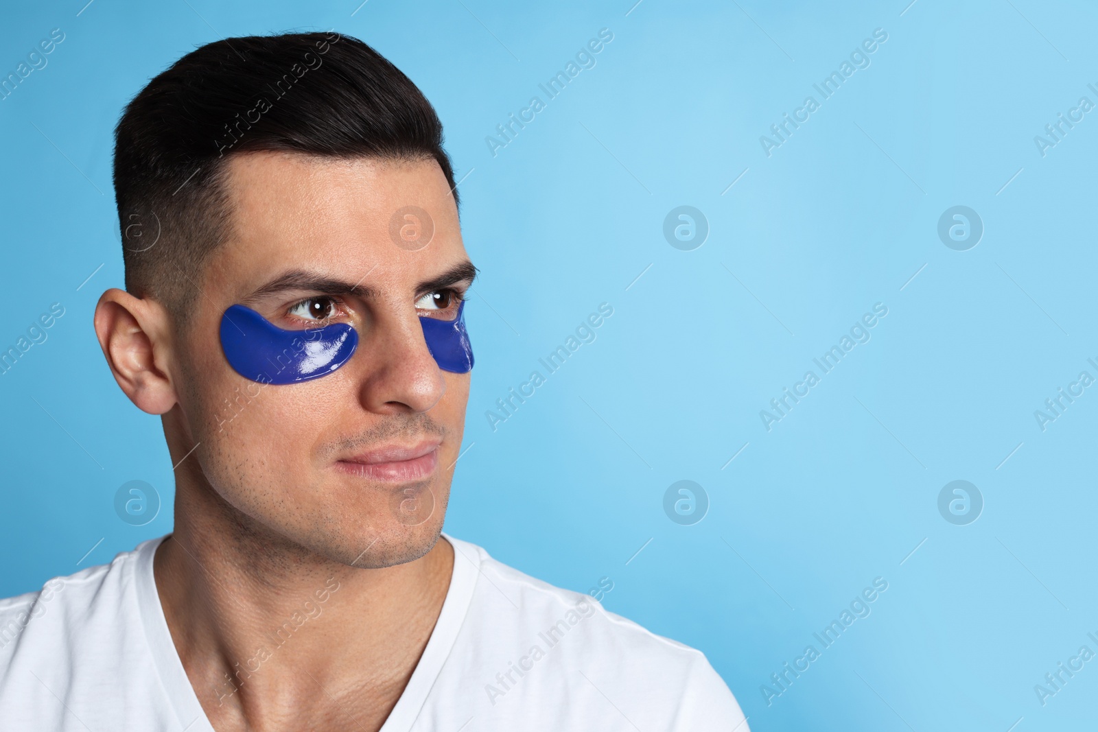 Photo of Man with under eye patches on light blue background. Space for text