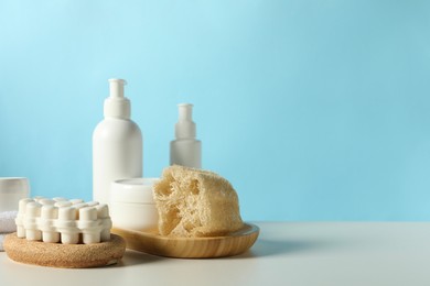 Different bath accessories on white table against light blue background. Space for text