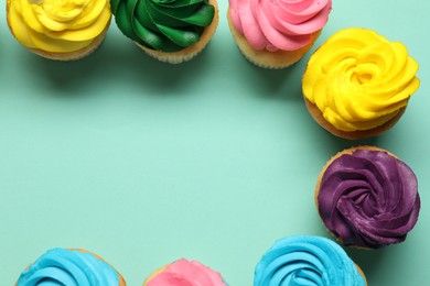 Photo of Delicious cupcakes with bright cream on turquoise background, flat lay. Space for text