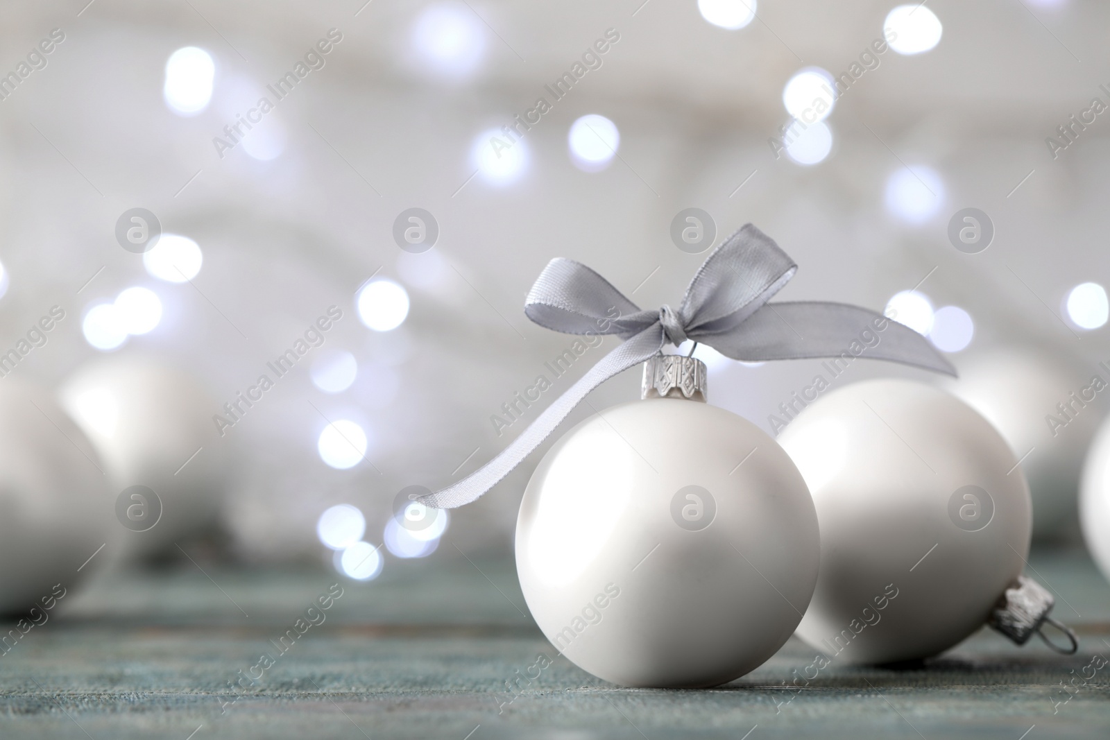 Photo of Beautiful Christmas balls on table against blurred festive lights. Space for text