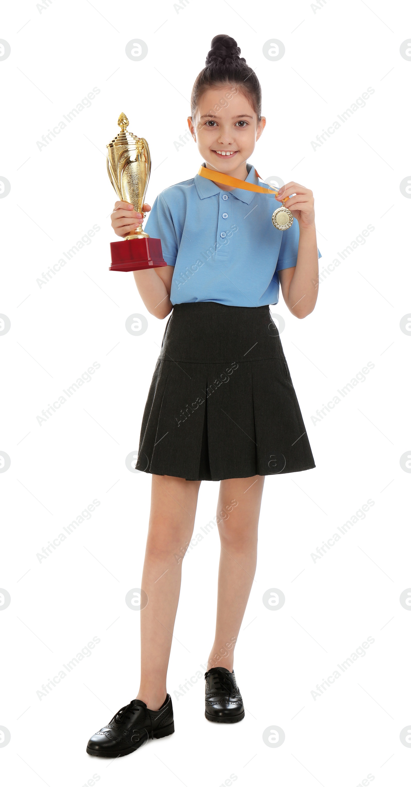 Photo of Happy girl in school uniform with golden winning cup and medal isolated on white