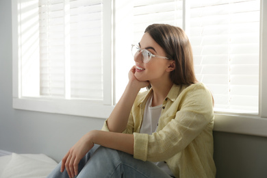 Photo of Beautiful young woman near window at home