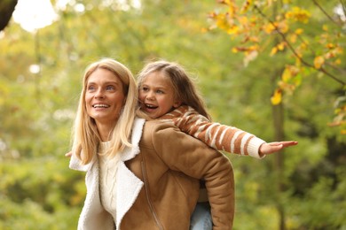 Photo of Happy mother having fun with her daughter in autumn park