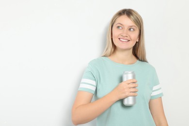 Beautiful happy woman holding beverage can on light background. Space for text