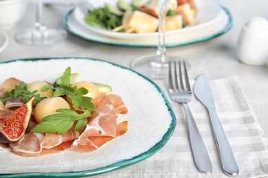 Photo of Plate with melon balls and prosciutto served on gray table