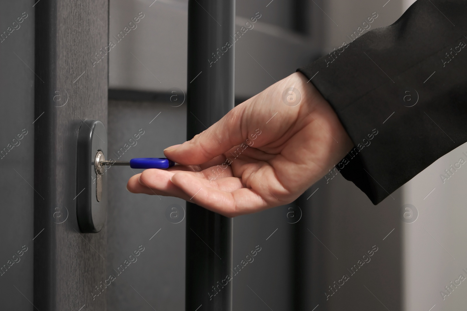 Photo of Woman unlocking door with key, closeup view