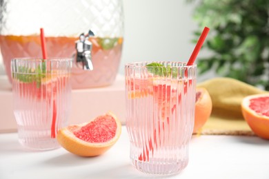 Photo of Delicious refreshing drink with grapefruit and mint on white table