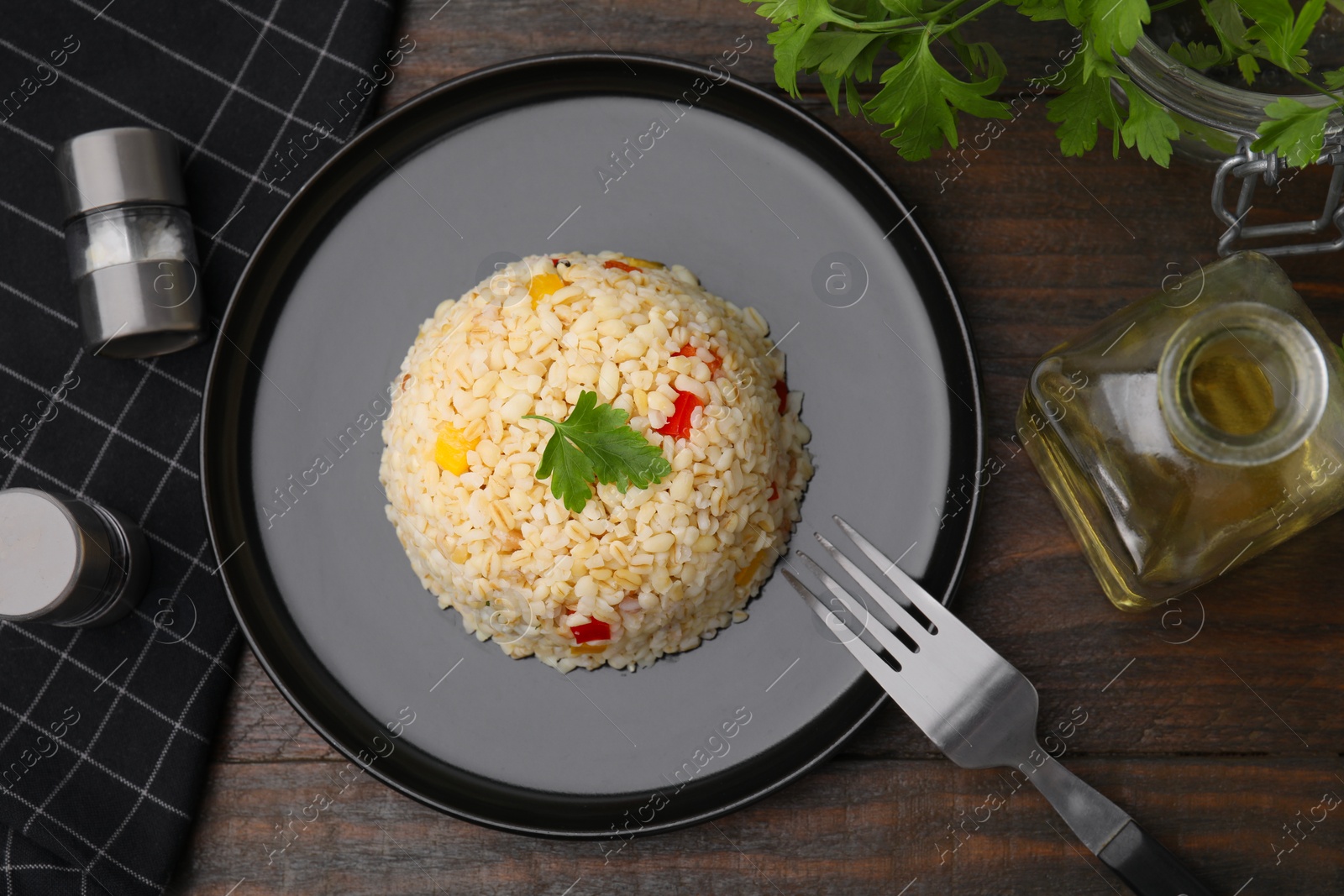 Photo of Delicious bulgur with vegetables and parsley served on wooden table, flat lay