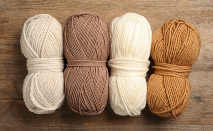 Photo of Soft woolen yarns on wooden table, flat lay