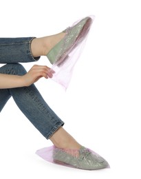 Woman wearing shoe covers onto her mules against white background, closeup