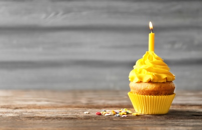 Photo of Delicious birthday cupcake with candle on table