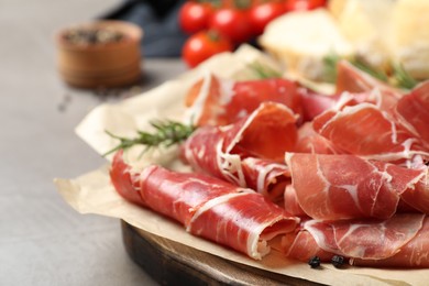 Photo of Slices of tasty prosciutto on grey table, closeup