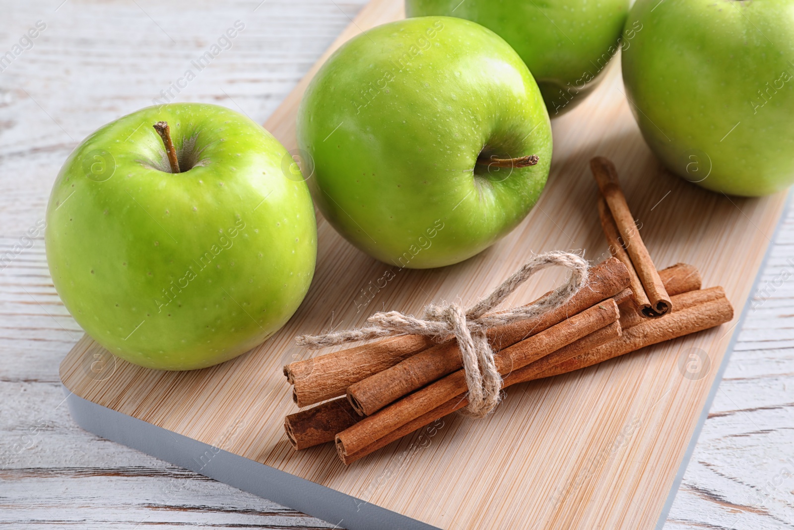 Photo of Fresh apples and cinnamon sticks on wooden board