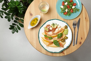 Photo of Flat lay composition with melon and prosciutto appetizer served on wooden table