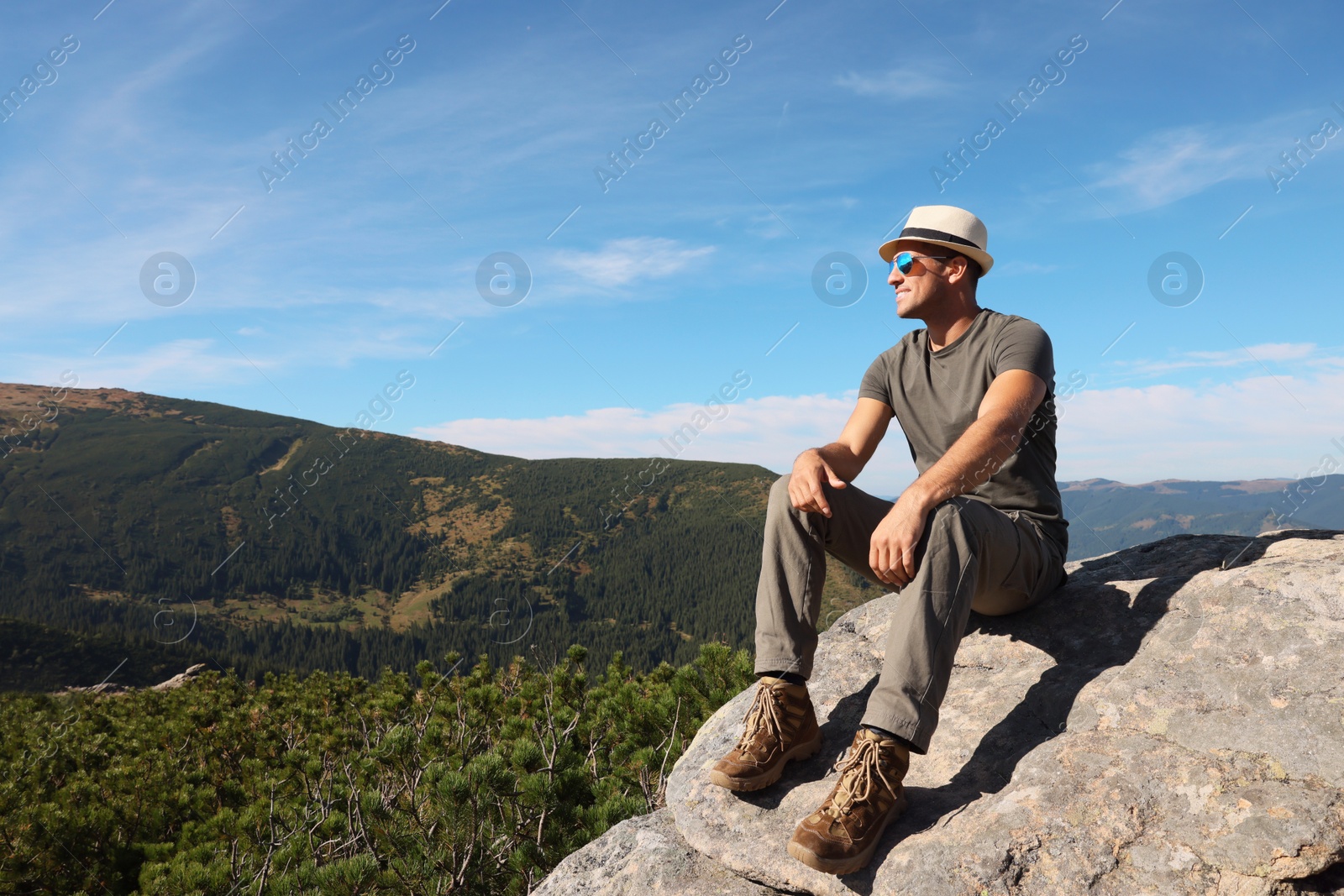 Photo of Man enjoying picturesque view on cliff in mountains. Space for text