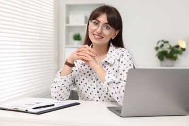 Portrait of smiling secretary at table in office