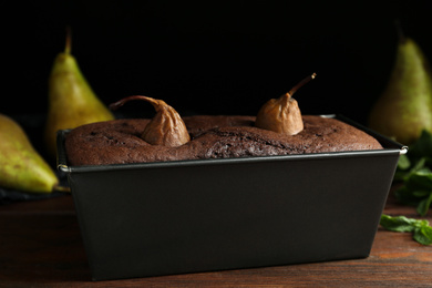 Photo of Tasty pear bread in baking form on wooden table. Homemade cake