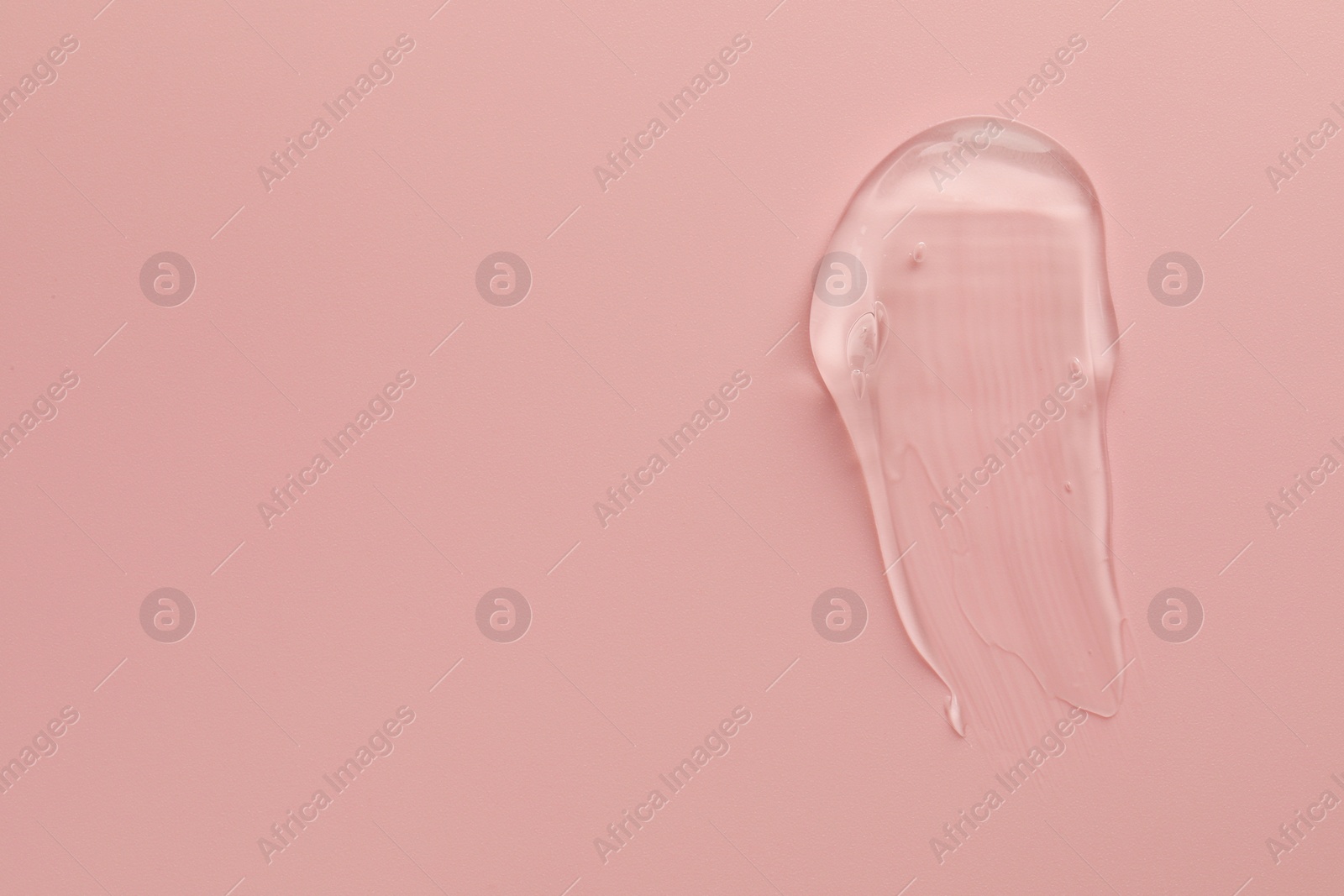 Photo of Smear of clear cosmetic gel on pink background, top view. Space for text