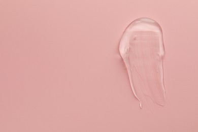 Photo of Smear of clear cosmetic gel on pink background, top view. Space for text
